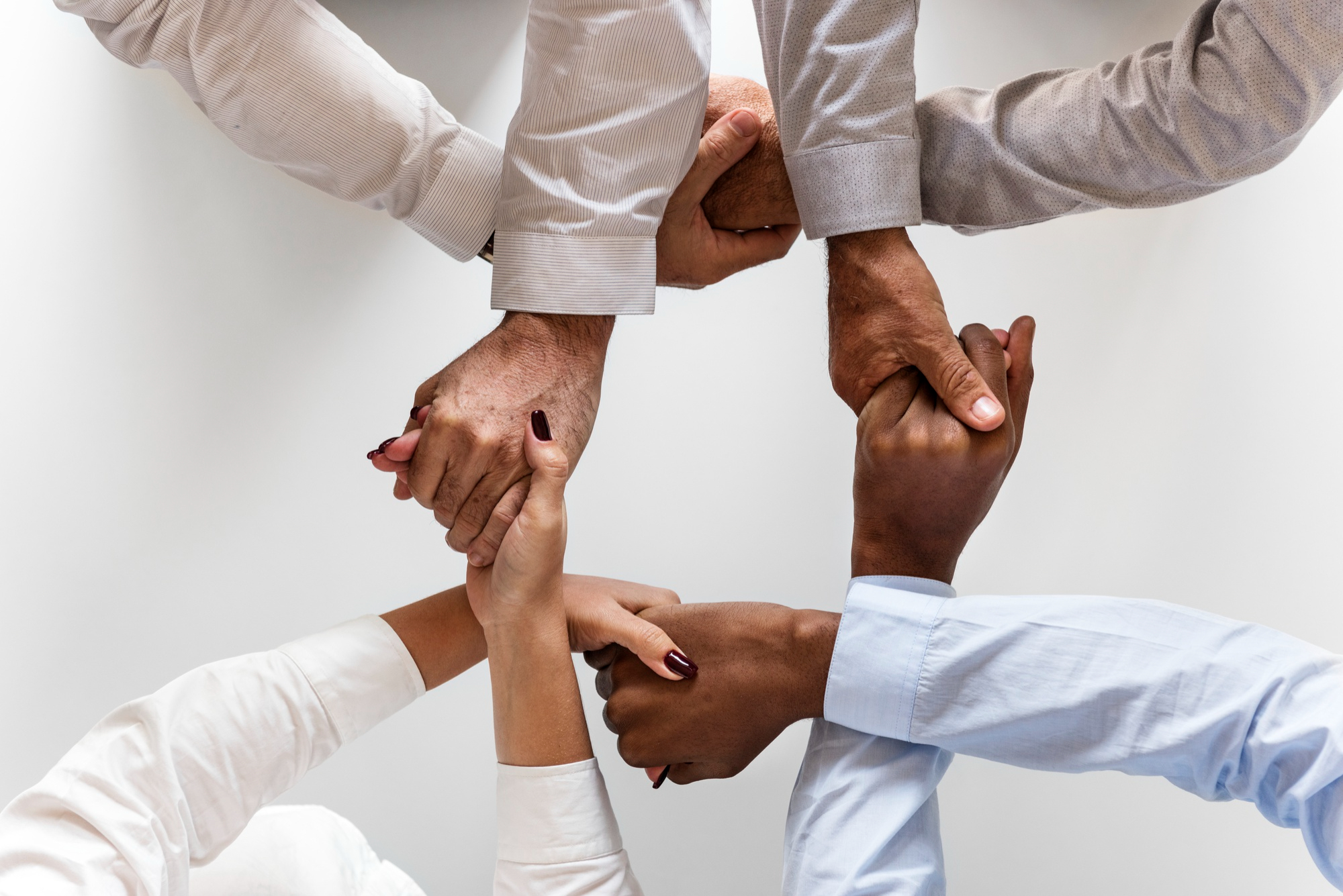 Mãos se entrelaçando e formando um elo, representando a liderança humanizada necessária para se ter times mais engajados.